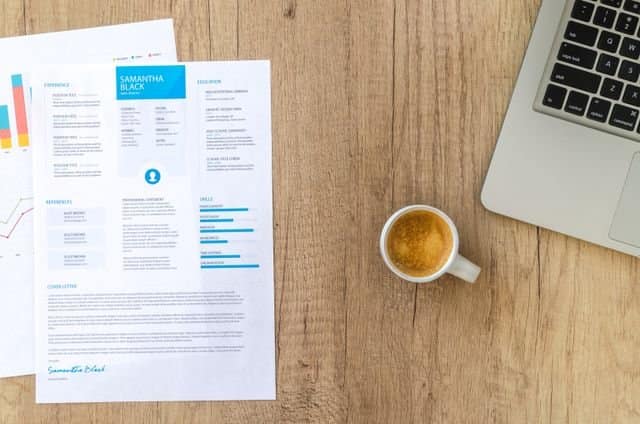 Academic CV for PhD Application 2026/2027 (International Students) Top view of a desk with resume, coffee cup, and laptop on a wooden surface, ideal for business concepts.